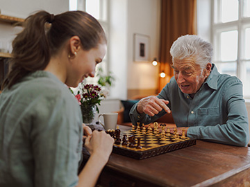 Senior man playing chess with carer