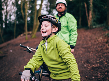 Boy on his mountain bike with his dad wearing a helmet