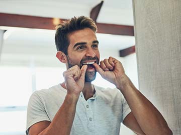 A man checking his front teeth in the mirror