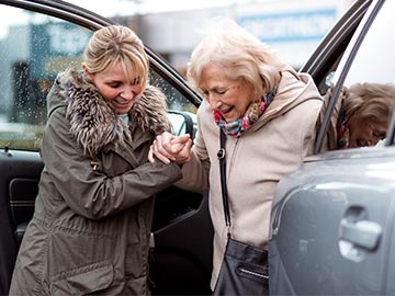 Volunteer helping a lady out the car to go shopping