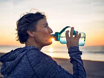 Lady drinking from water bottle at the beach