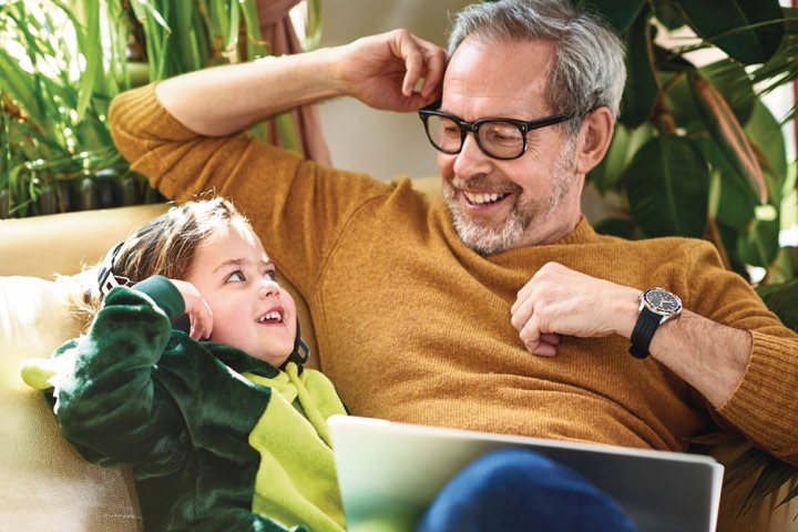 Father and daughter laughing together while using a laptop