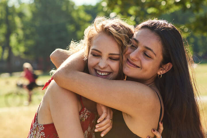 Two friends hugging in the park in the sunshine